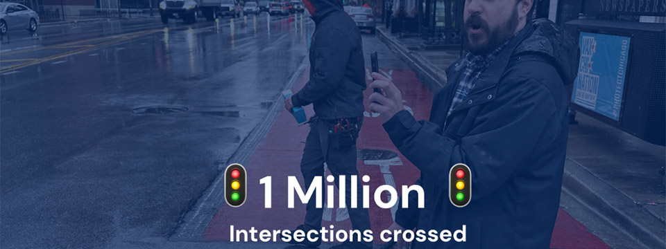 A banner containing text announcing the 1 million streets crossed with OKO. In the background a user is holding their phone to recognize the pedestrian traffic light.