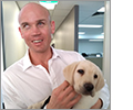 Photo of Ben Moxey holding Ferris, Guide Dog in Training.